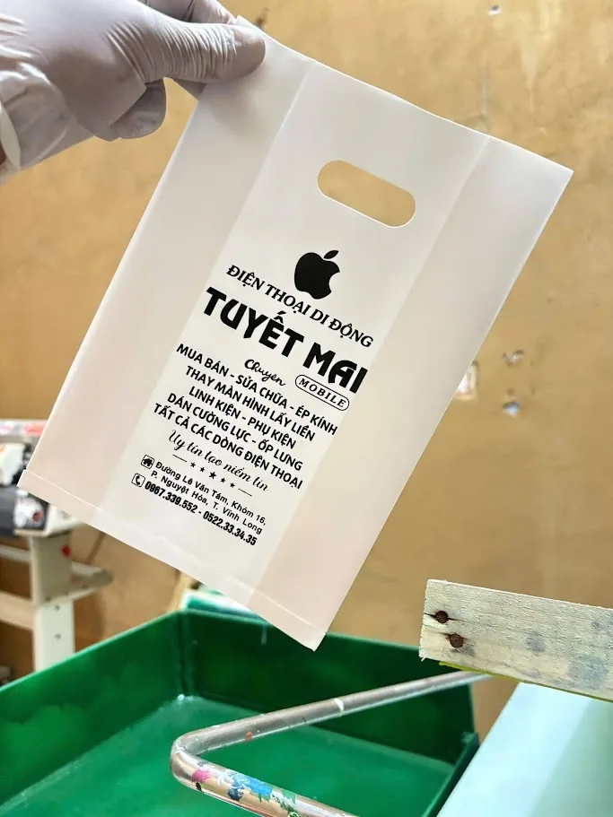 Túi trắng đã in được cầm bên khu vực in tại IST